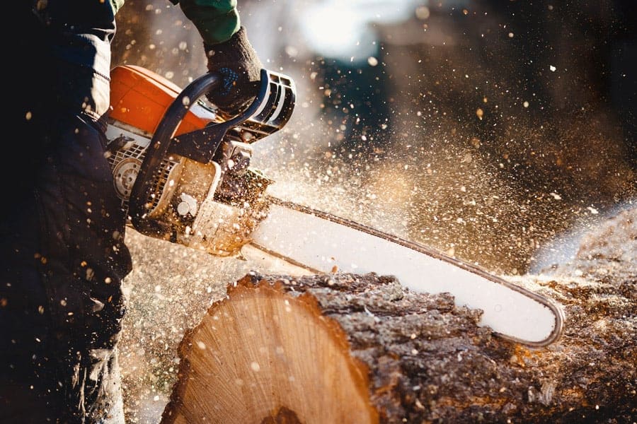 A person cutting through a log with a chainsaw.