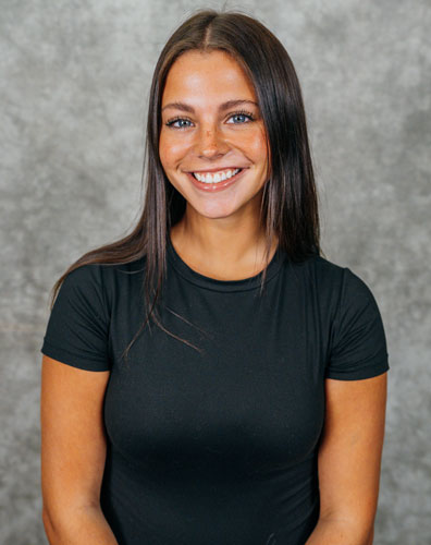 A young woman with long dark hair wearing a black t-shirt. She is smiling at the camera.